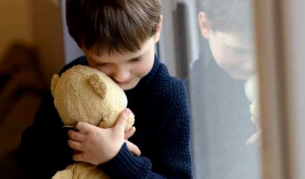 Boy is hugging a teddy bear.