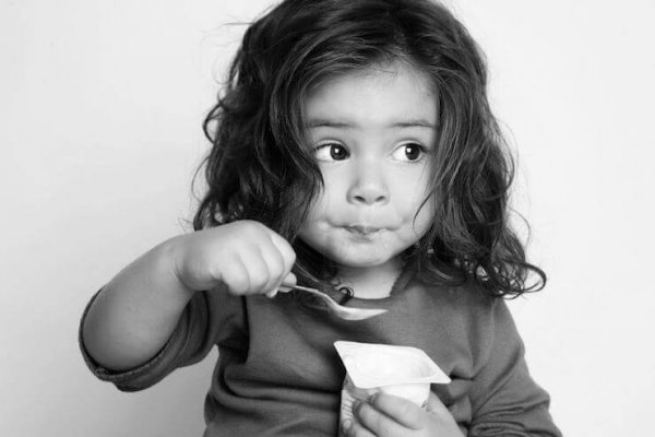 Girl eating yogurt to improve concentration in children.