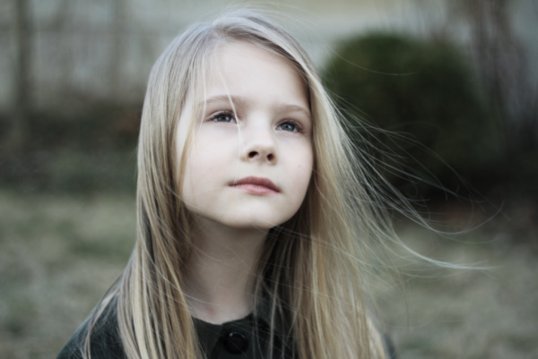 A child looking up at the sky in the wind.