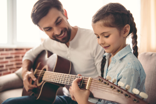 Father and daughter playing the guitar.