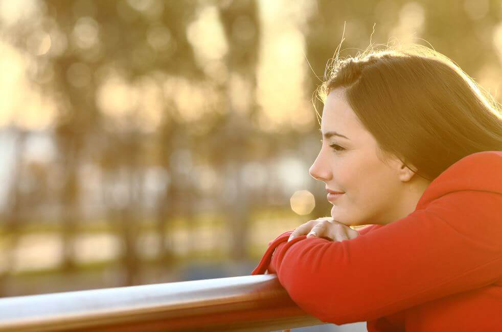 A woman smiling into the sun, thoughtful.