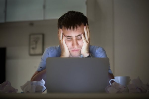 A man working from his laptop, exhausted.