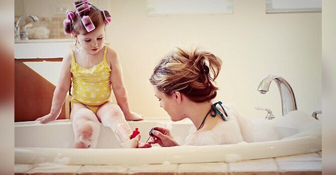 A mother painting her daughter's nails in the bath.