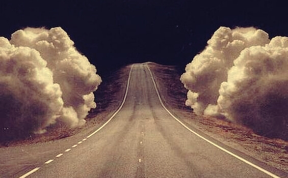 A road with clouds on the sides.