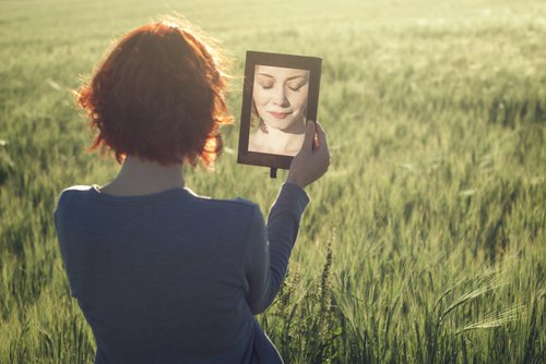 A woman is looking at herself in a mirror.