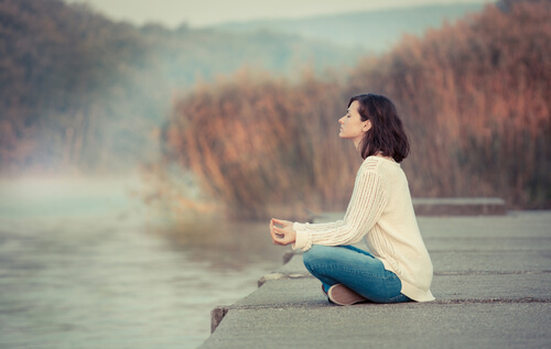 Woman meditating by a lake.