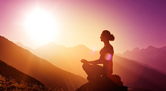 Woman is meditating on a mountain.
