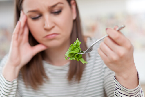 Orthoexia: a woman looking unhappily at lettuce.
