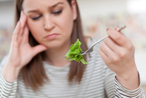 Orthoexia: a woman looking unhappily at lettuce.