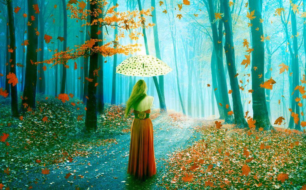 A woman with an umbrella is walking through the woods.