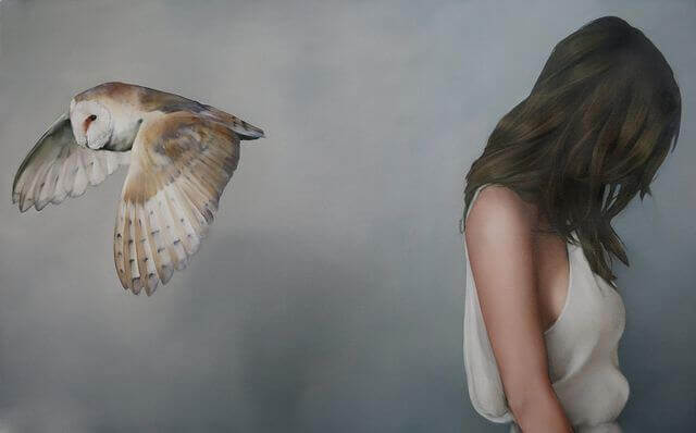 Woman with her head down and a bird flying away from her.