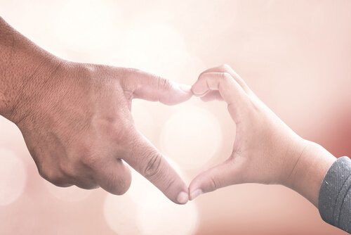 A father and his son are making a heart with their hands.