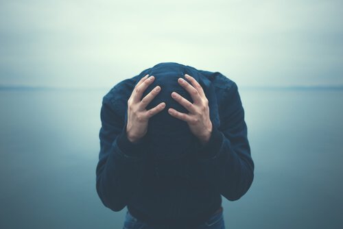 A man with agoraphobia is holding his head.