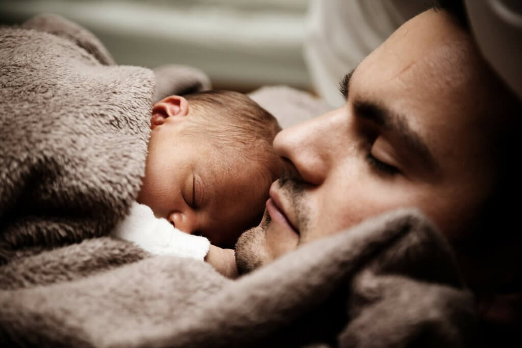 A man is sleeping with a baby, love as a source of motivation.