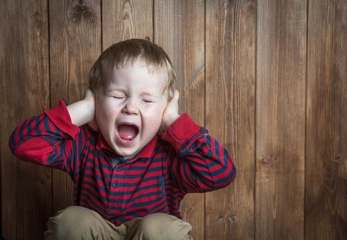 A child screaming and covering his ears.