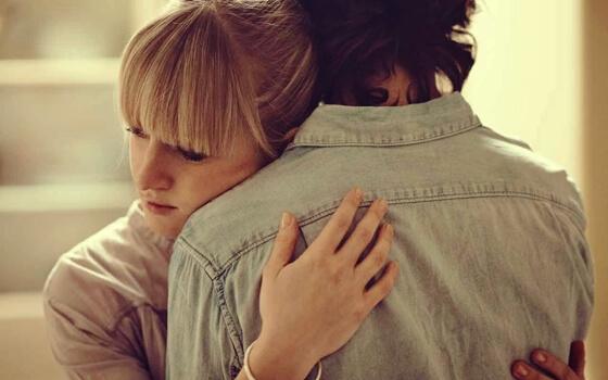 A sad couple hugging.