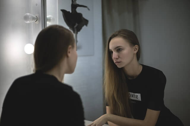 Self-concept as pictured by a woman looking at herself in the mirror.