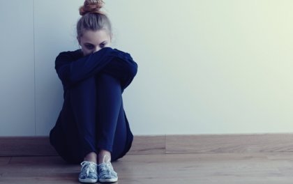 A woman upset with her knees to her chest.