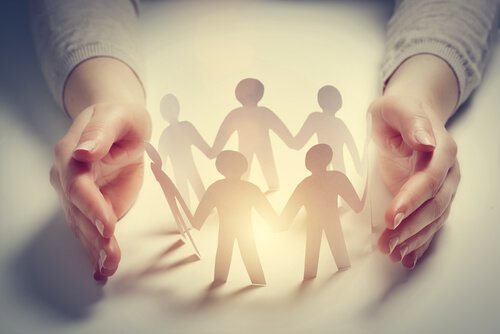 Hands surrounding a circle of paper figures.