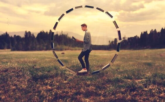 A man is inside a circle of books.