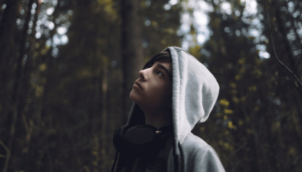 A teen with headphones looking up at the sky.