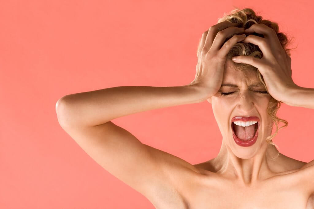 a woman is gripping hear head and screaming.
