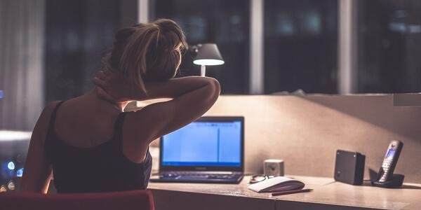 Overworked woman in a toxic job at night.
