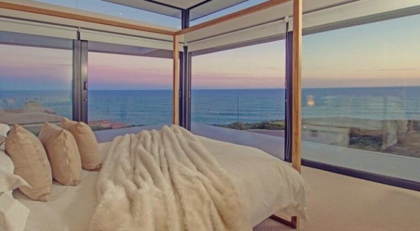 A luxury room with glass walls on the beach.