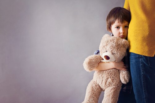 A sad boy with a teddy bear.