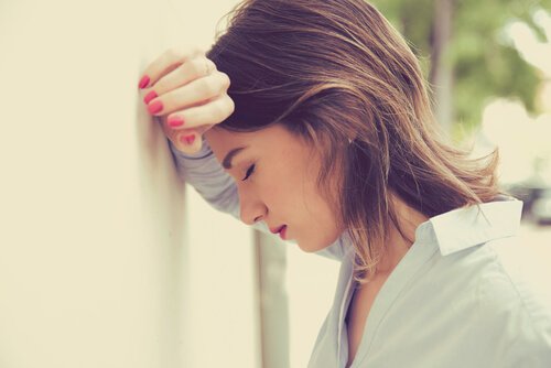 woman dealing with emotional exhaustion leaning her head against the wall