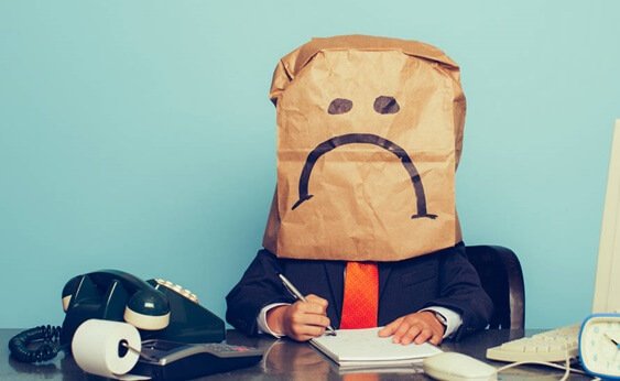 A man at work with a sad face bag over his face.