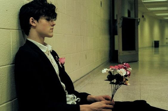 boy sitting in hallway with flowers symbolizing wanting to leave your partner but not being able to