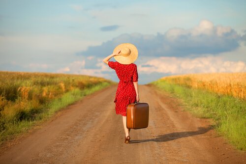 woman with wanderlust syndrome walking down a path with her suitcase