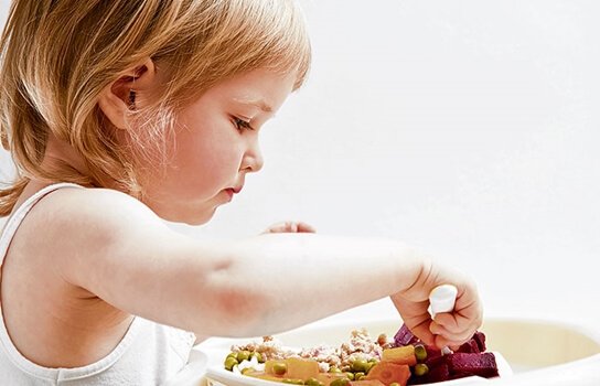 Girl eating vegetables independently