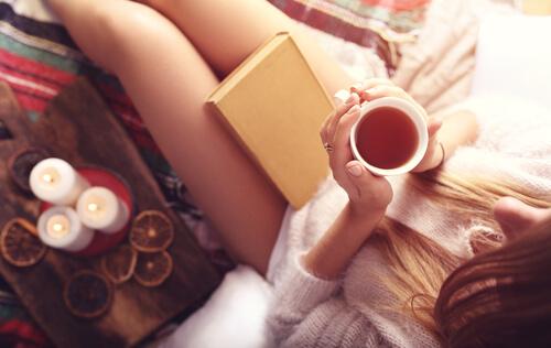 woman reading a book while drinking tea
