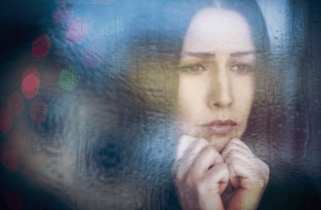 depressed woman looking through window