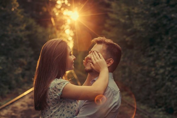 A girl surprises her boyfriend by covering his eyes.