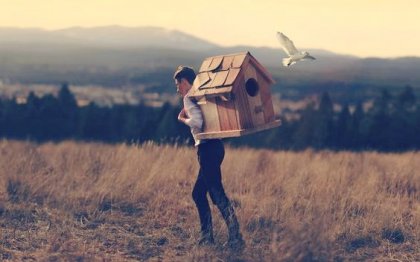 Man carrying a bird house on his back.