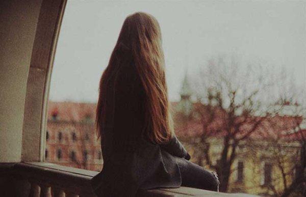 Woman sitting on balcony confronting her solitude.
