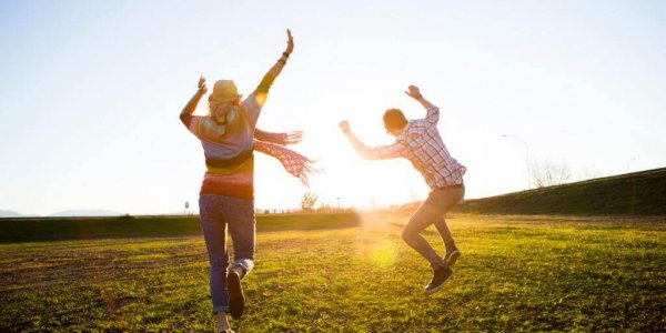 Couple jumping in a field.