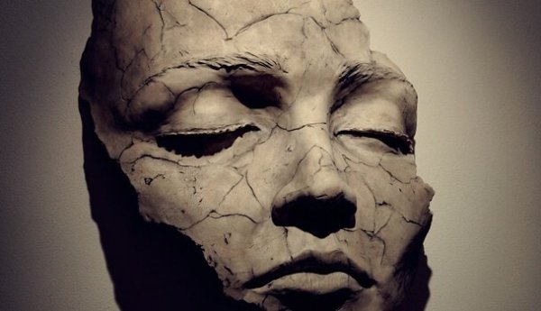 Cracked face representing emotional fragility.