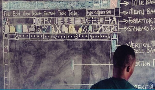 Ghanaian teacher in class in front of blackboard.