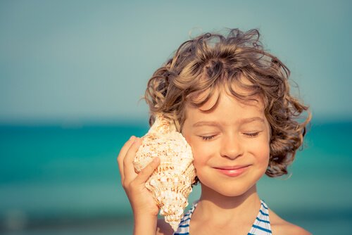 A girl listening to a sea shell.