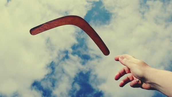 Hand throwing a boomerang, a metaphor for how you deserve the love you give to other people.