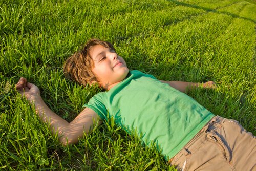 Little boy laying in the grass with a smile on his face.