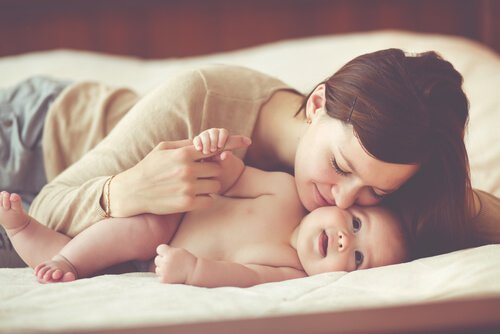 Mother kissing her baby in bed.