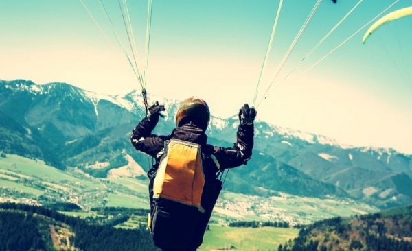 man flying through sky with parachute on