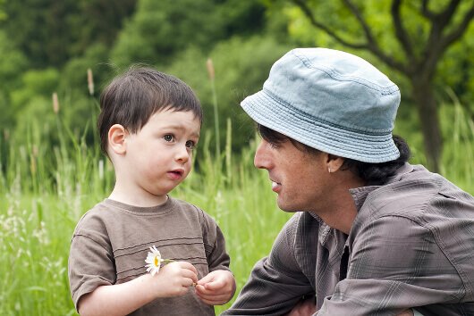 A man talking to his son in a field of flowers.