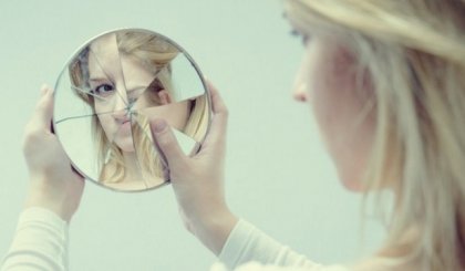 Woman looking in a broken mirror.