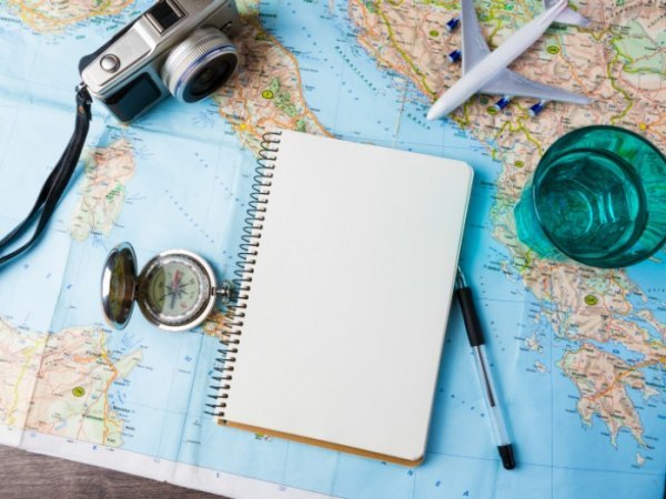 Notebook, camera, and pen on top of a map.